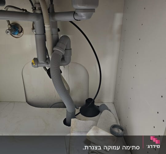 צנרת מתחת לכיור עם פומפה ומטלית